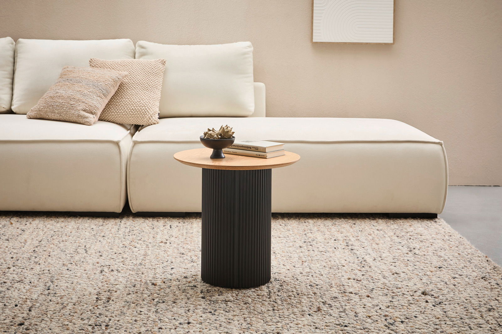 Stylife Beistelltisch GROOVE WOOD Moderner Beistelltisch mit runder Holzplatte und schwarzem, geripptem Sockel, frontal vor einem cremefarbenen Sofa auf einem Teppich.