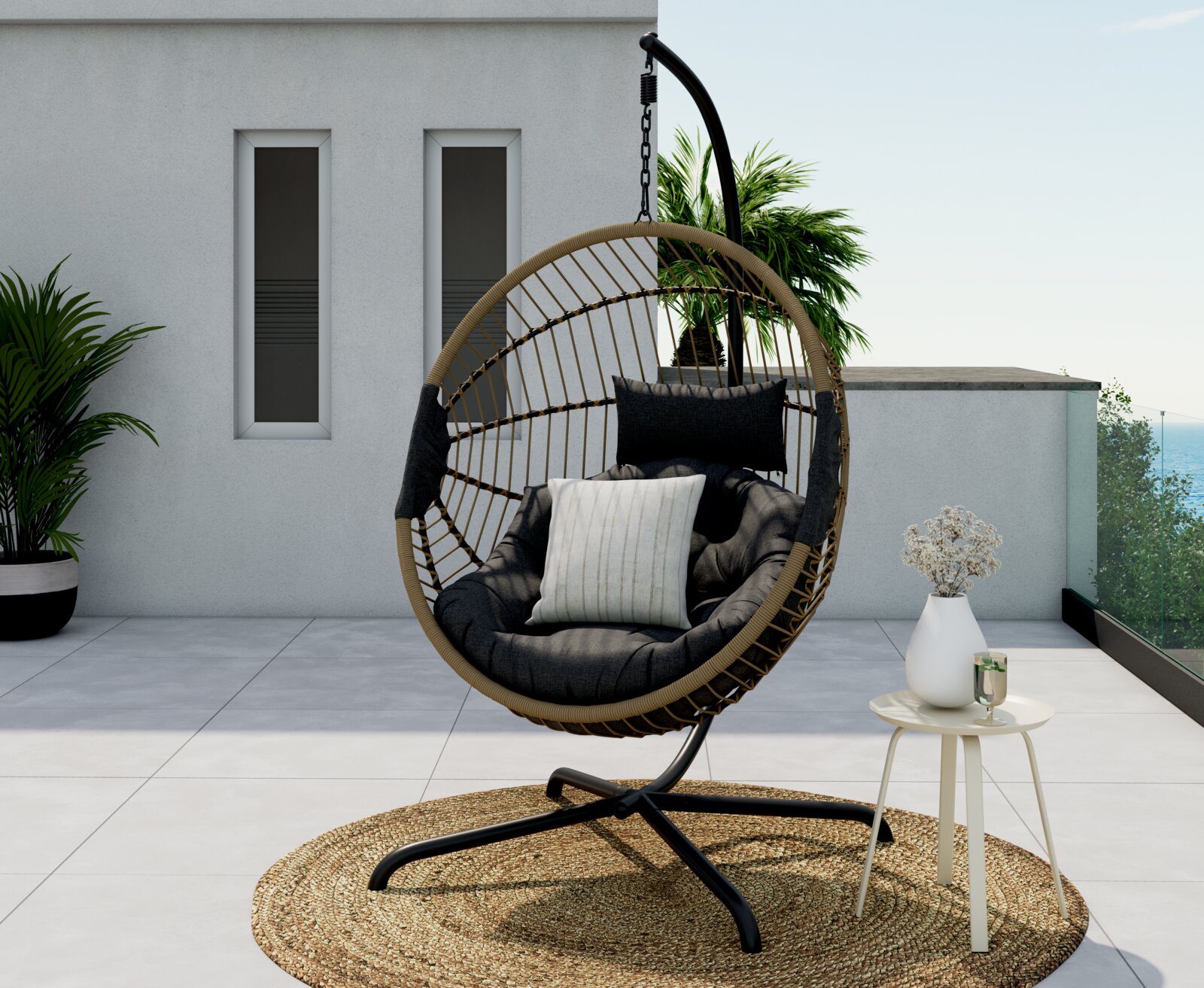 Ambia Garden Hängesessel PADUA Moderner Hängesessel auf einer Terrasse, seitliche Perspektive, mit Kissen und einem kleinen Beistelltisch mit Vase und Getränk.