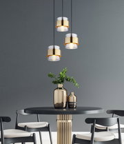 Moderne Hängeleuchte mit drei goldenen Lampenschirmen über einem eleganten Esstisch, seitliche Perspektive.