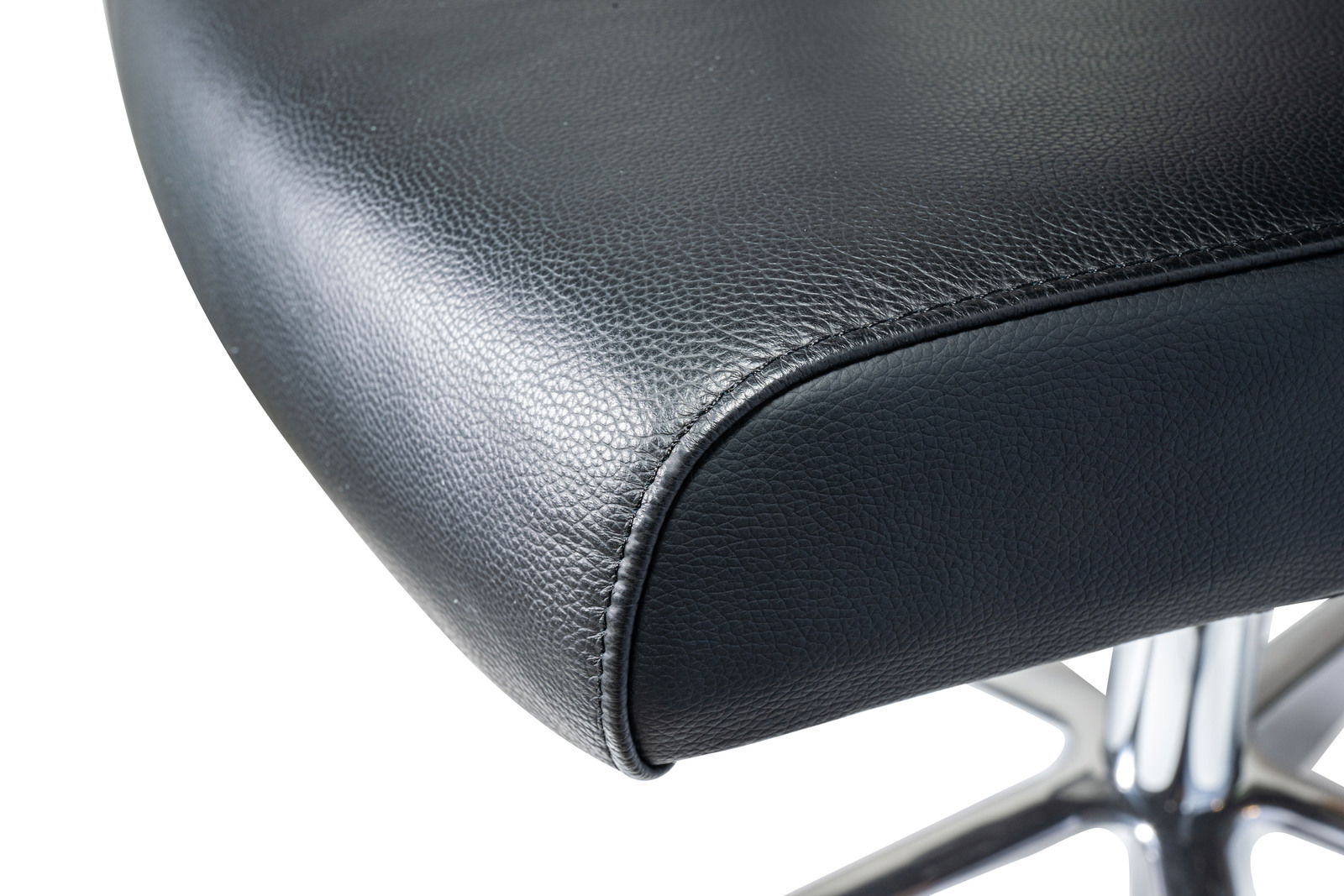 Nahaufnahme eines schwarzen Ledersitzes eines Chefsessels mit verchromtem Fußgestell, seitliche Perspektive.