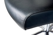 Nahaufnahme eines schwarzen Ledersitzes eines Chefsessels mit verchromtem Fußgestell, seitliche Perspektive.