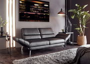 Modernes zweisitziges Sofa in schwarzem Leder, seitliche Perspektive, umgeben von stilvoller Dekoration und Pflanzen.