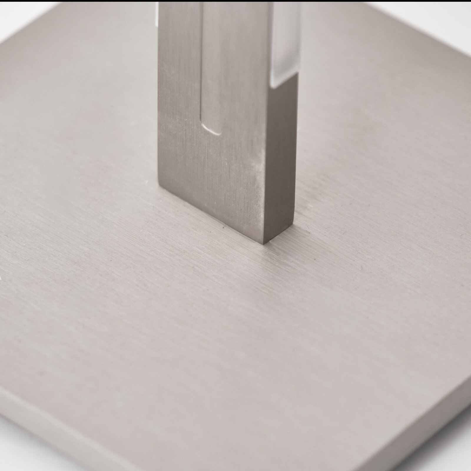 Grossmann LED-Stehleuchte AERA Detailansicht aus schräger Nahperspektive auf einen eckigen Metallfuß mit gebürsteter Oberfläche auf einer hellen Bodenplatte