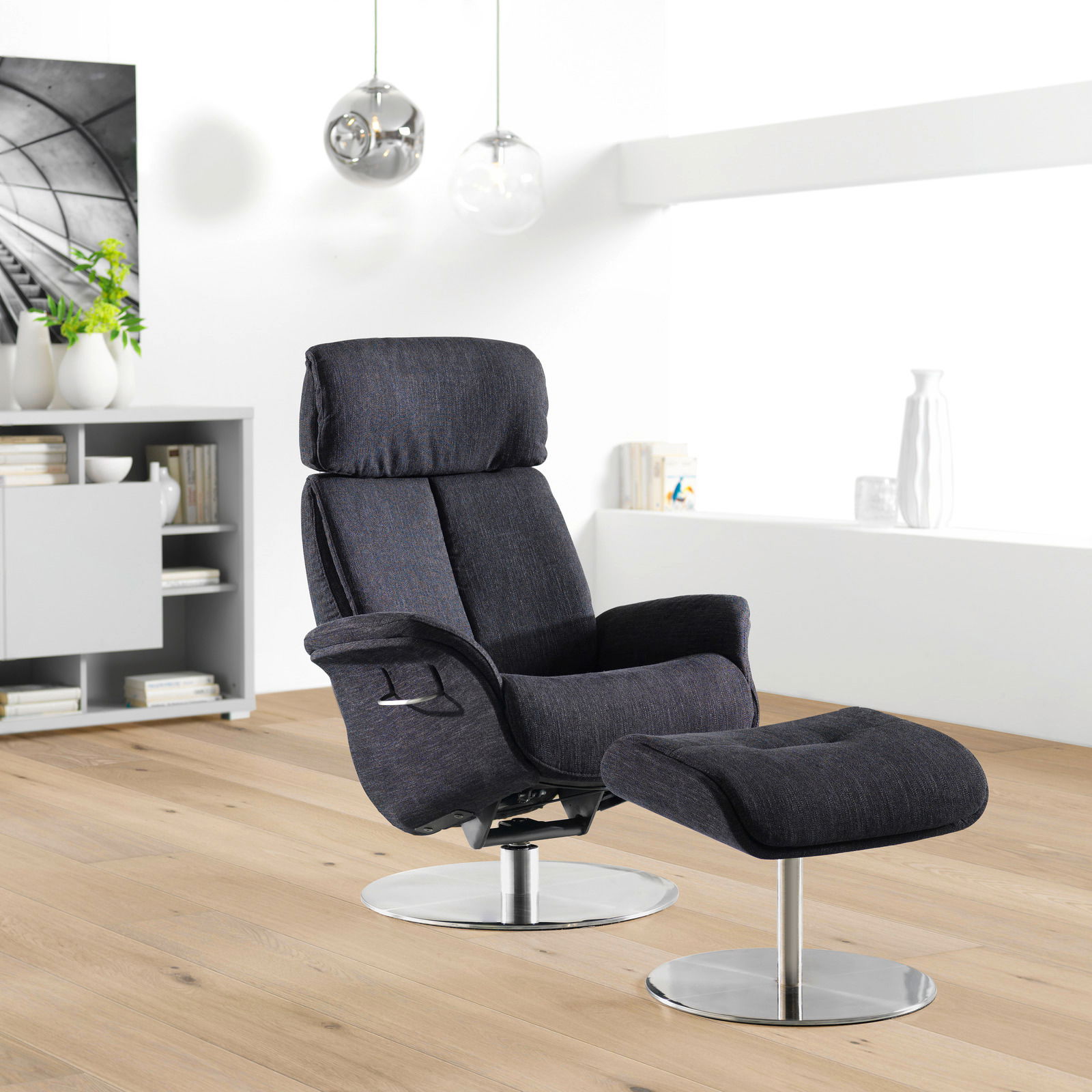 Moderner Relaxsessel mit Hocker in dunklem Stoffbezug, seitliche Perspektive, auf hellem Holzboden in einem stilvollen Wohnzimmer.