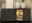 Modernes Sideboard mit drei Schubladen und einem beleuchteten Vitrinenfach, dekoriert mit zwei weißen Vasen und einem gerahmten Bild, frontal betrachtet.