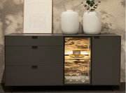 Modernes Sideboard mit drei Schubladen und einem beleuchteten Vitrinenfach, dekoriert mit zwei weißen Vasen und einem gerahmten Bild, frontal betrachtet.