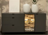 Modernes Sideboard mit drei Schubladen und einem beleuchteten Vitrinenfach, dekoriert mit zwei weißen Vasen und einem gerahmten Bild, frontal betrachtet.