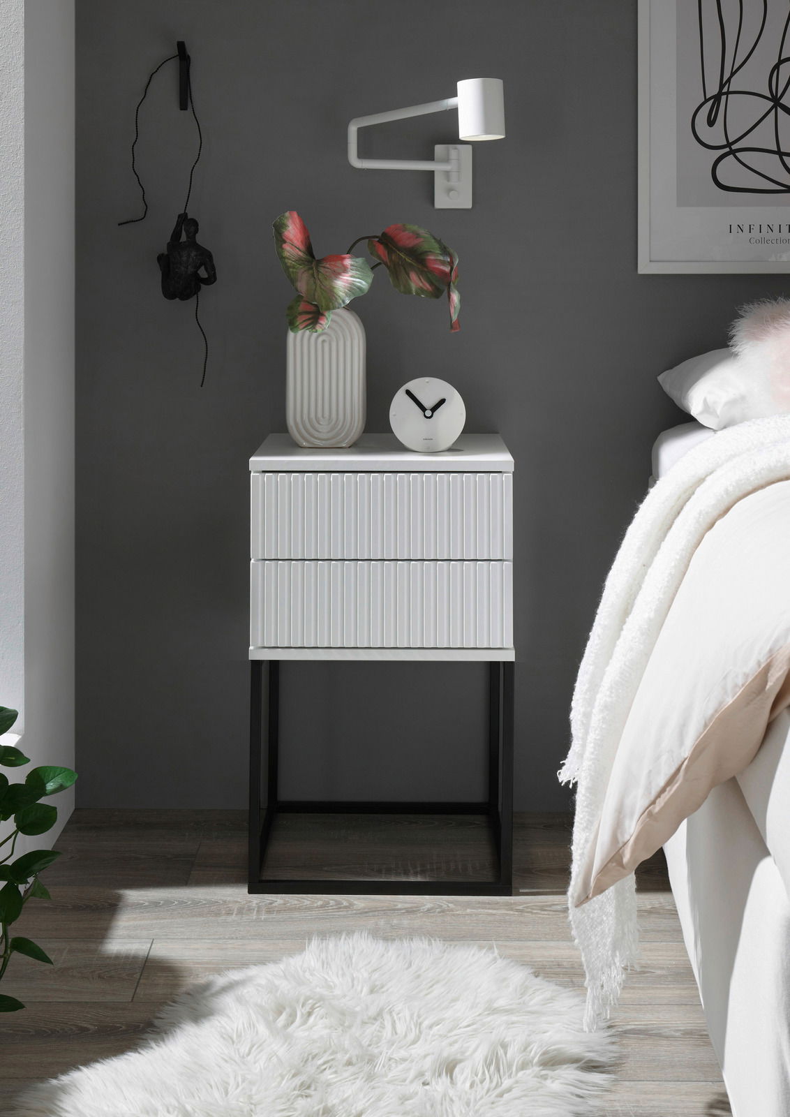 Moderne Nachtkommode mit geriffelter Oberfläche, dekoriert mit einer Vase und einer Uhr, aus frontaler Perspektive fotografiert.