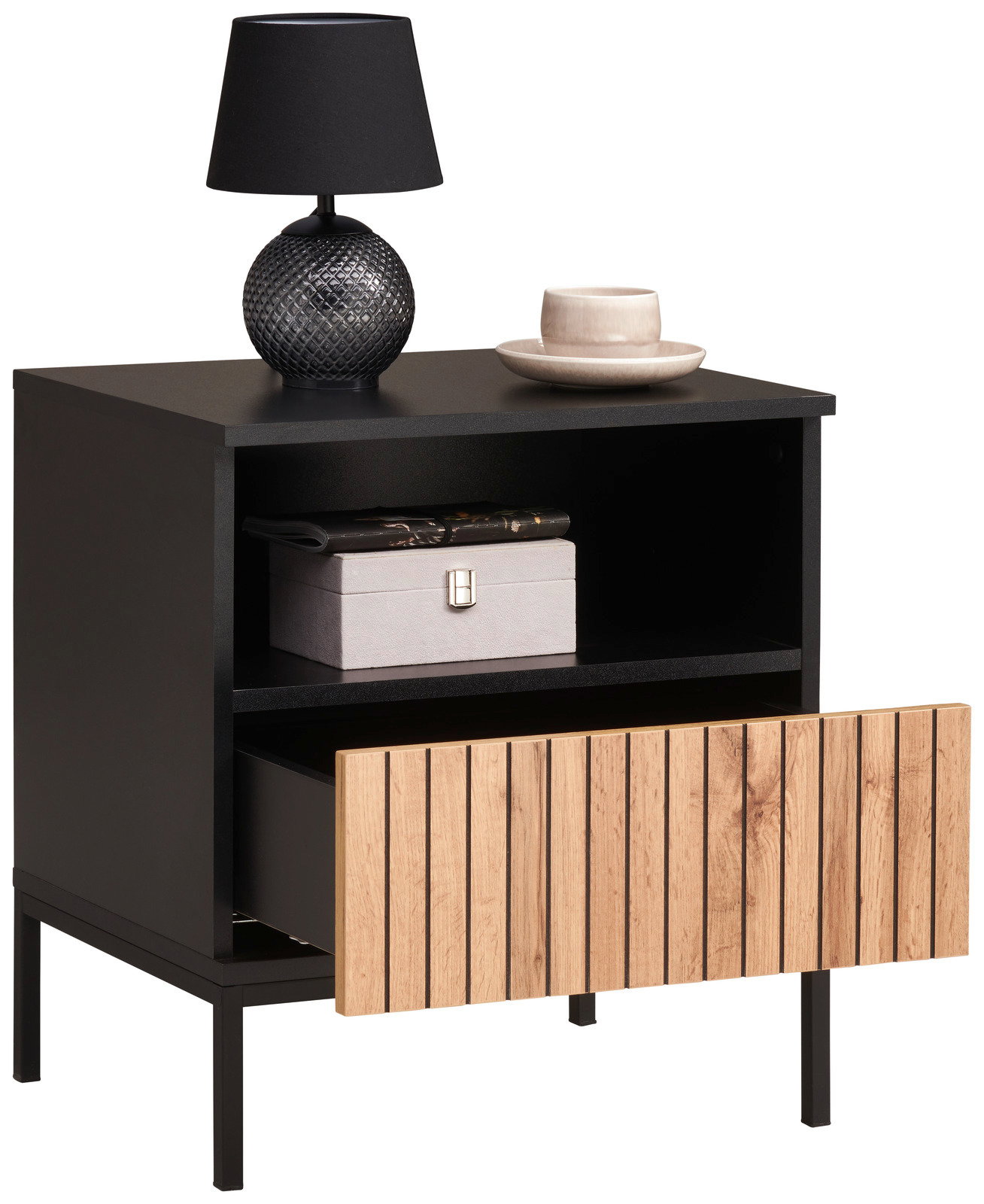 Schwarze Nachtkommode mit offener Schublade aus Holzlamellen, darauf eine schwarze Lampe und eine Tasse, seitliche Perspektive