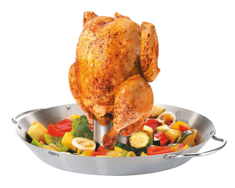 Hähnchengriller mit Gemüse-Wok, seitliche Perspektive, zeigt ein gegrilltes Hähnchen auf einem Edelstahlständer über einer Schale mit buntem Gemüse.