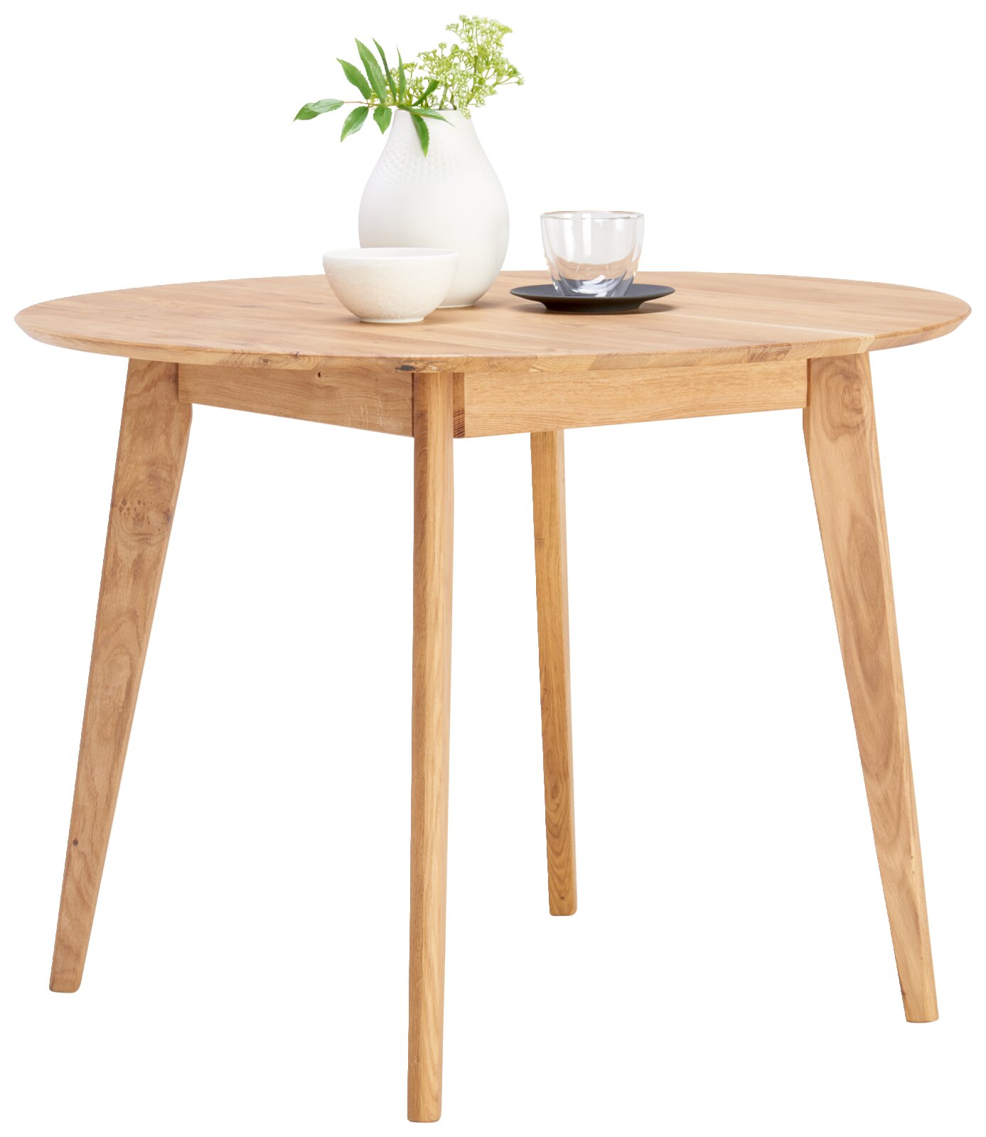 Cantus Eettafel TALLINN Runder Esstisch aus Holz mit schräger Perspektive, dekoriert mit einer weißen Vase, einer Schale und einem Glas.