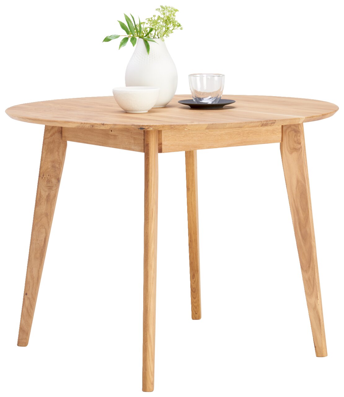 Runder Esstisch aus Holz mit schräger Perspektive, dekoriert mit einer weißen Vase, einer Schale und einem Glas.