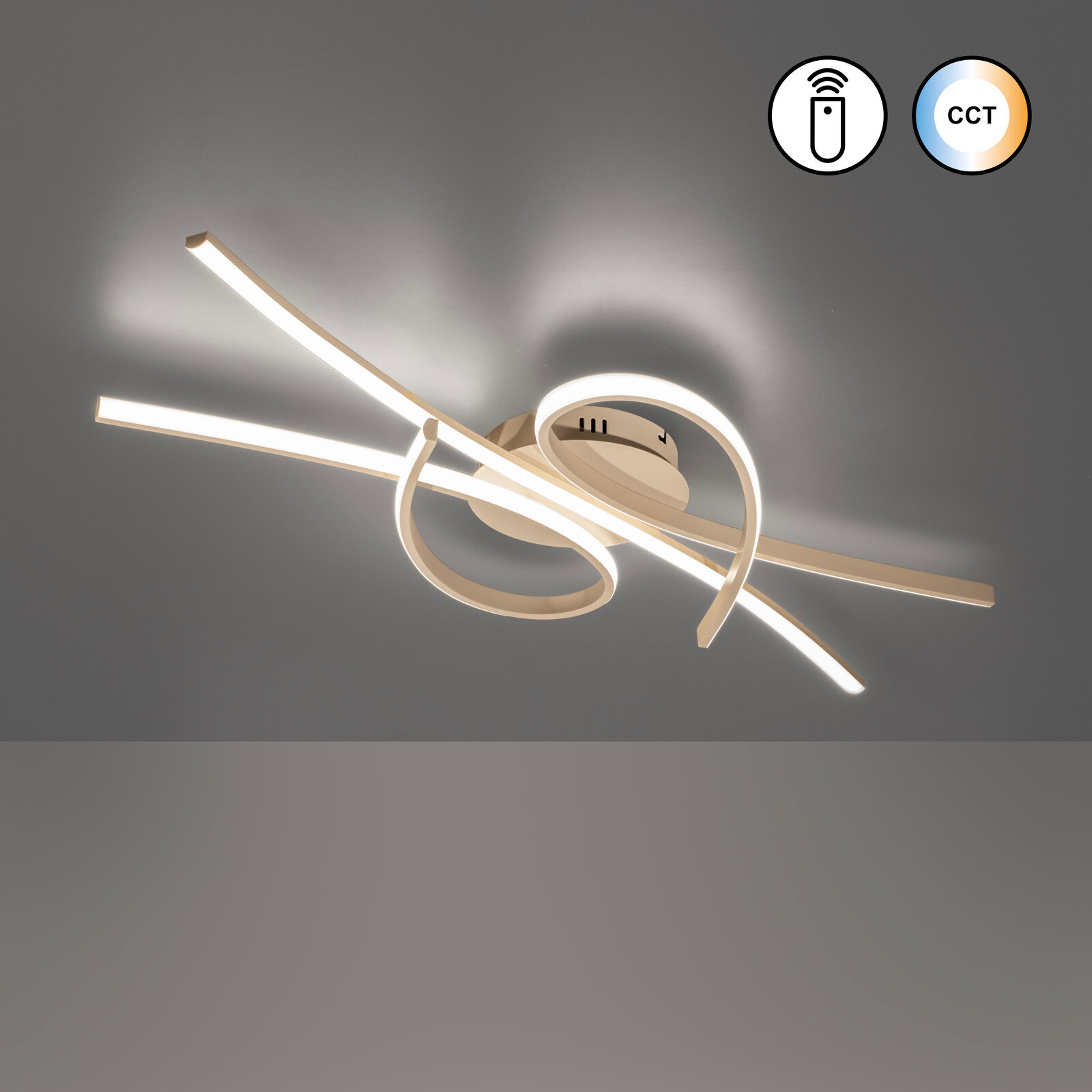 Moderne LED-Deckenleuchte in geschwungenem Design mit warmweiß leuchtenden Lichtbändern und CCT-Funktion, Ansicht von unten in leichter Schrägperspektive an der Decke montiert.