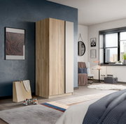 Moderner Kleiderschrank in heller Holzoptik mit weißer Seitenfront im Schlafzimmer, schräg von vorn links fotografiert