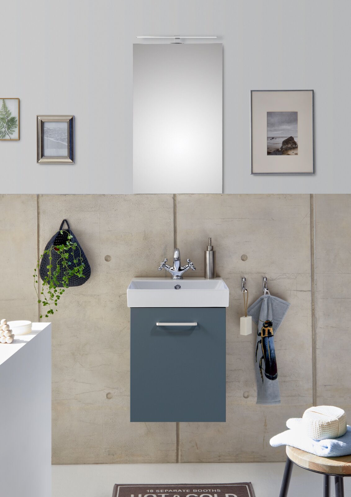 Modernes Badezimmer mit wandhängendem Waschtischunterschrank in Blau und weißem Waschbecken, darüber Spiegel mit schmaler LED-Leuchte; Frontalansicht auf das Waschplatz-Set.