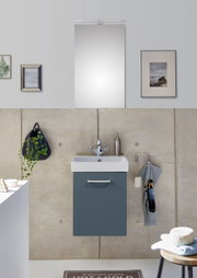 Modernes Badezimmer mit wandhängendem Waschtischunterschrank in Blau und weißem Waschbecken, darüber Spiegel mit schmaler LED-Leuchte; Frontalansicht auf das Waschplatz-Set.