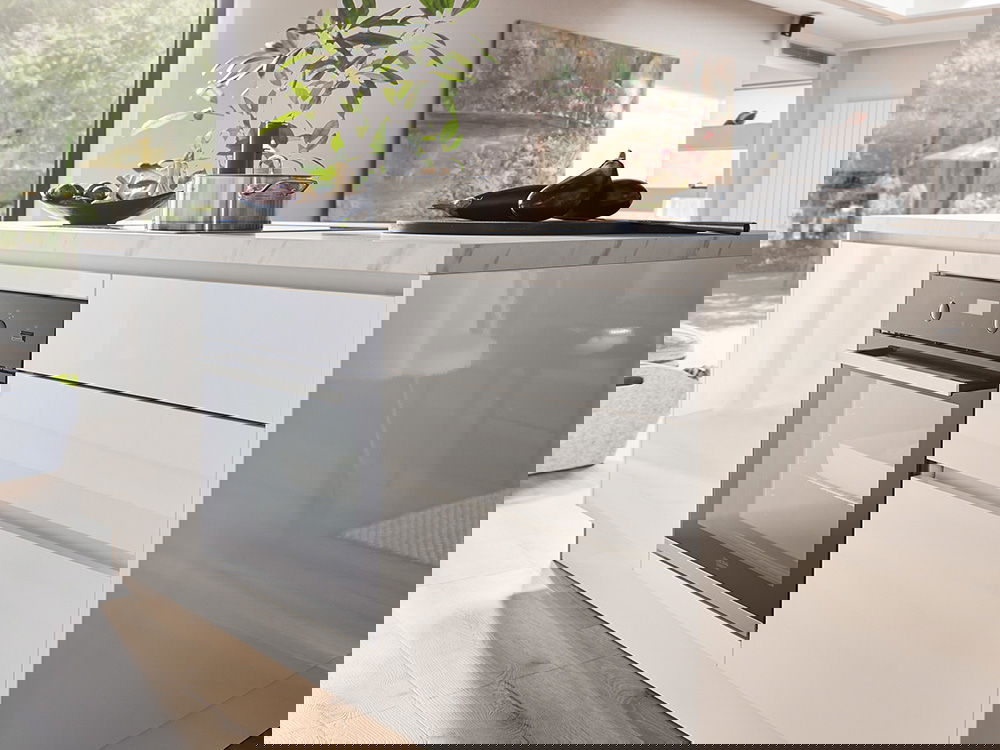 Moderne Kücheninsel mit glänzend weißen Schränken und einem eingebauten Ofen.