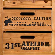 Nahaufnahme eines rustikalen Bar- und Servierwagens aus Holz mit Schubladen, die mit industriellen Grafiken und Schriftzügen wie 'CAUTION' und '31st ATELIER GRAPHIC' verziert sind.