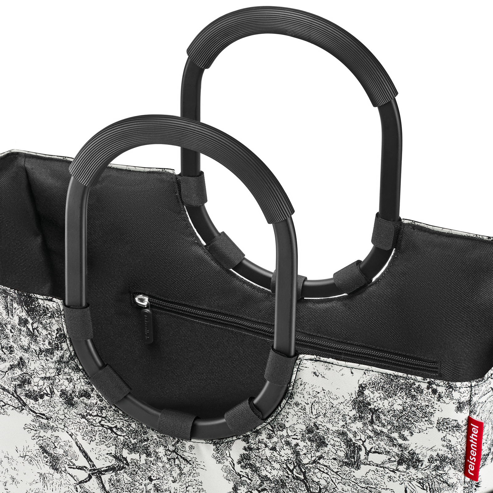 Nahaufnahme einer stilvollen Einkaufstasche mit schwarzen Griffen und einem schwarz-weißen Baum-Muster, seitliche Perspektive.