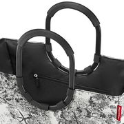 Nahaufnahme einer stilvollen Einkaufstasche mit schwarzen Griffen und einem schwarz-weißen Baum-Muster, seitliche Perspektive.