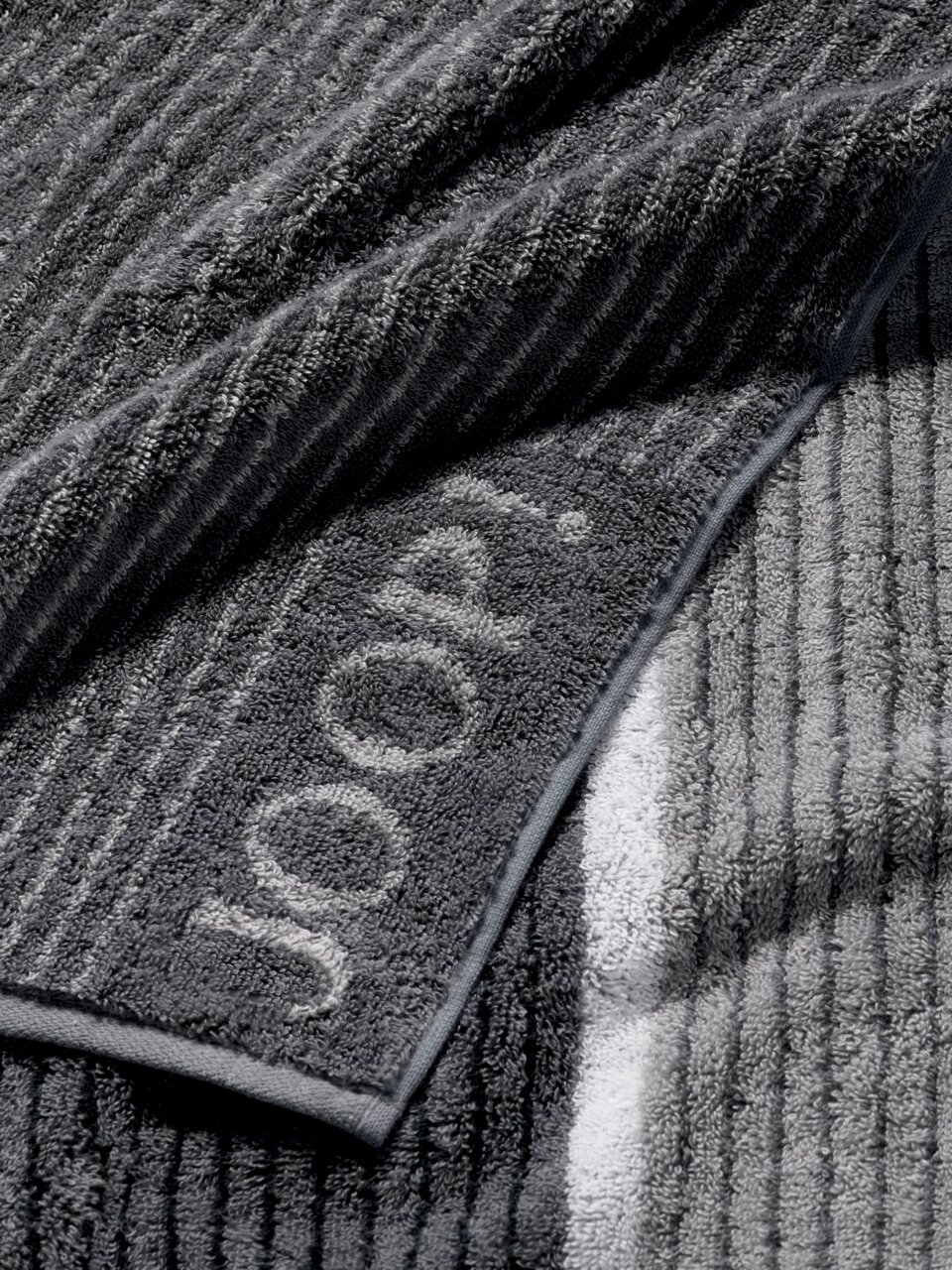 Gästetuch in Nahaufnahme, graue Streifen mit eingewebtem Schriftzug 'JOOP!'