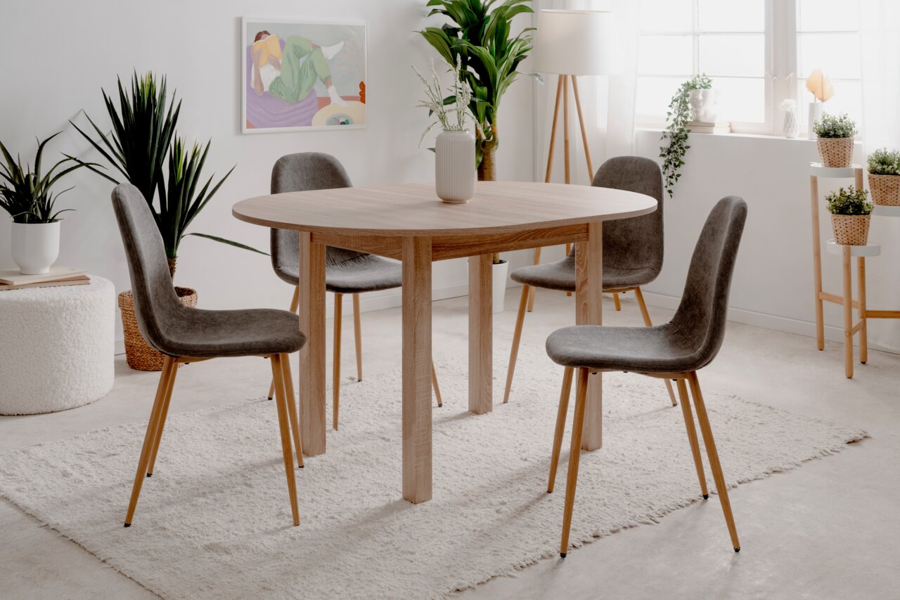 Runder Esstisch aus Holz mit vier grauen Stühlen in einem hellen, modernen Raum, seitliche Perspektive.