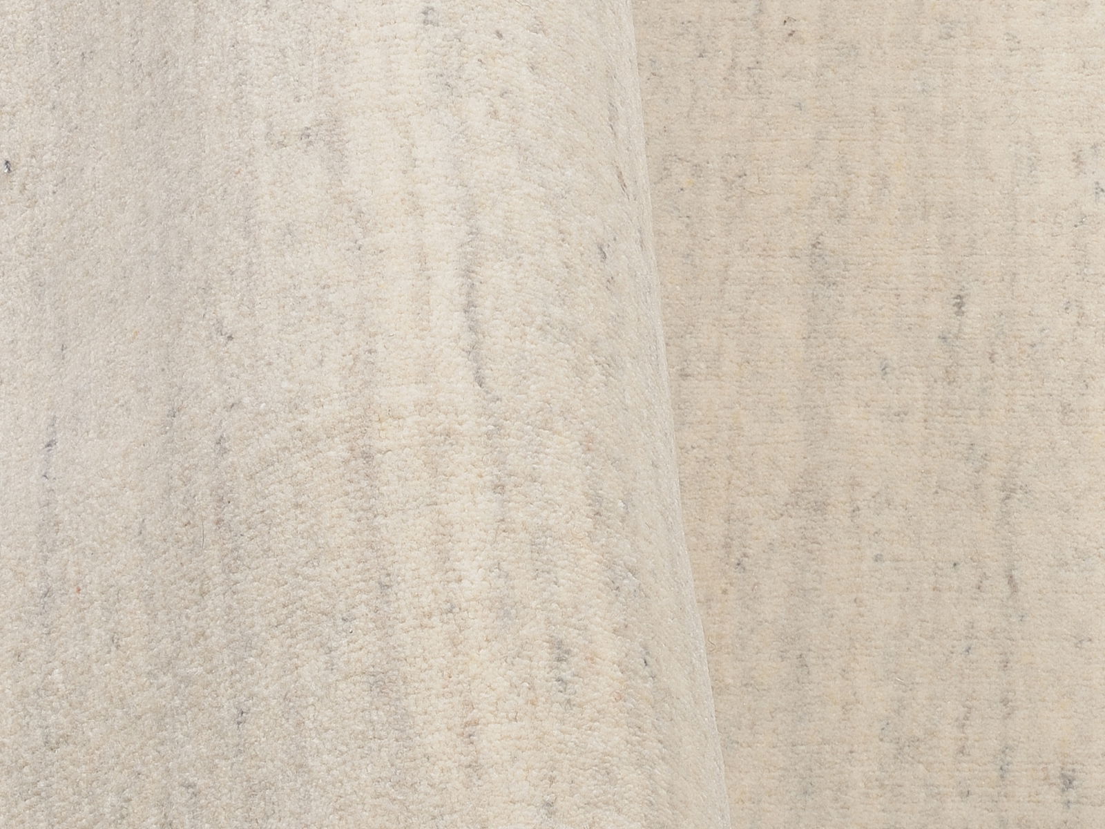 Nahaufnahme eines hellen Wollteppichs mit leichter Textur, seitliche Perspektive