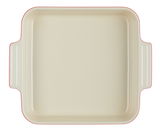 Vogelperspektive auf eine quadratische, cremefarbene Auflaufform mit roten Rändern und seitlichen Griffen.