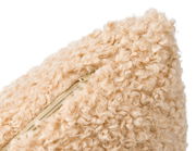 Nahaufnahme einer beigen, flauschigen Kissenhülle mit sichtbarem Reißverschluss.