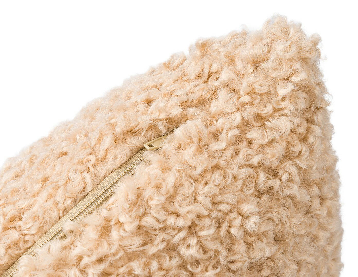 Nahaufnahme einer beigen, flauschigen Kissenhülle mit sichtbarem Reißverschluss.