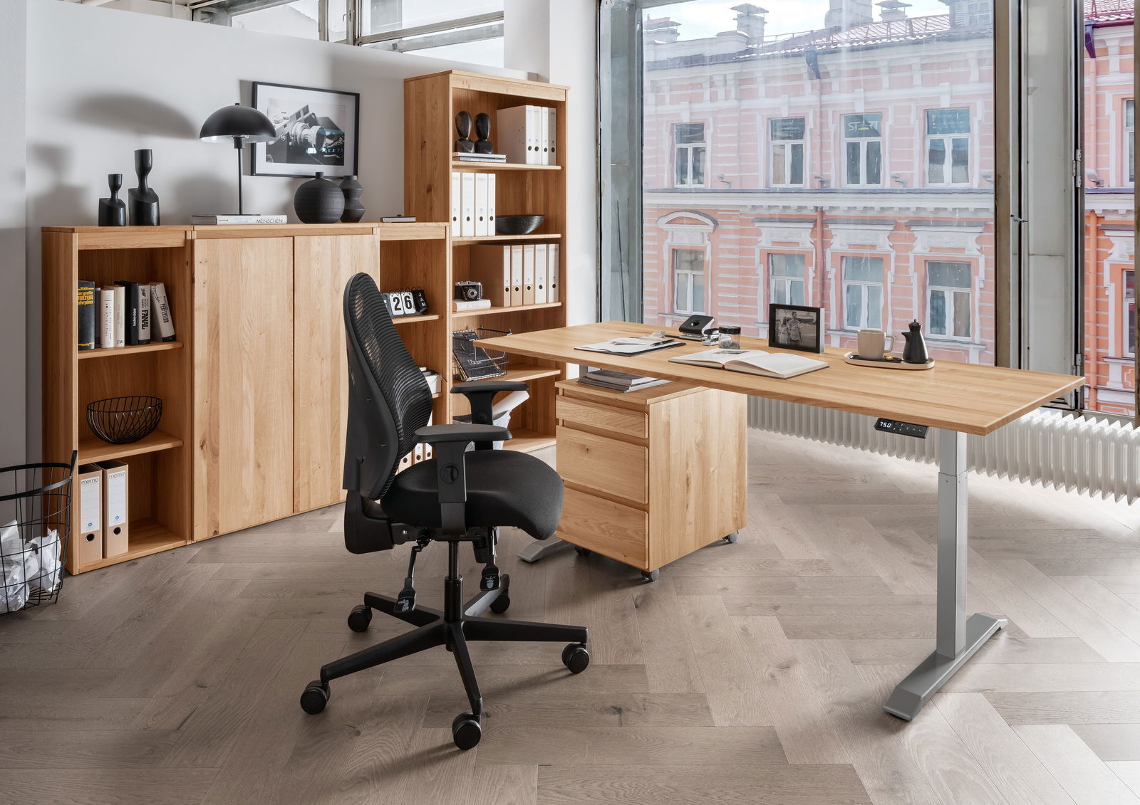 Linea Natura Hoogkast DURABLE OFFICE Moderne Büroumgebung mit einem höhenverstellbaren E-Schreibtisch aus Holz, einem schwarzen Bürostuhl und einem Aktenschrank, seitliche Perspektive.