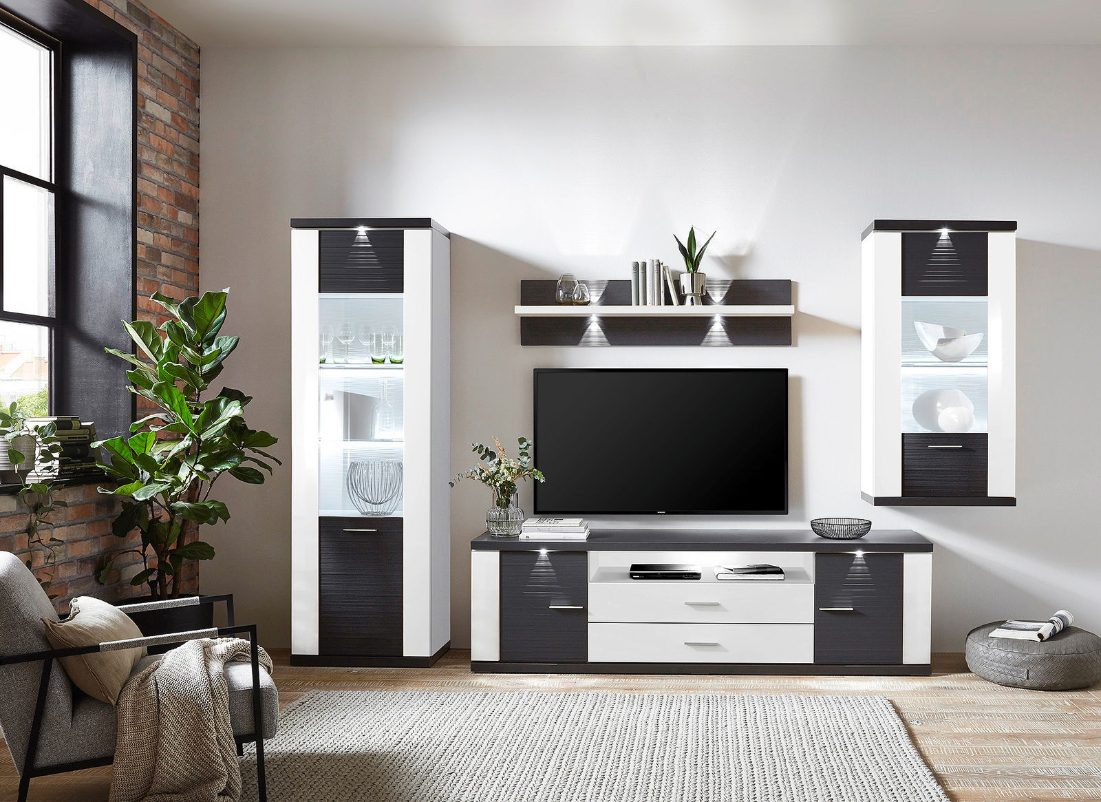 XORA Wandkombination MANHATTAN Moderne Wandkombination in einem Wohnzimmer, bestehend aus zwei hohen Schränken, einem TV-Board und einem Wandregal, aus der Frontalperspektive betrachtet.