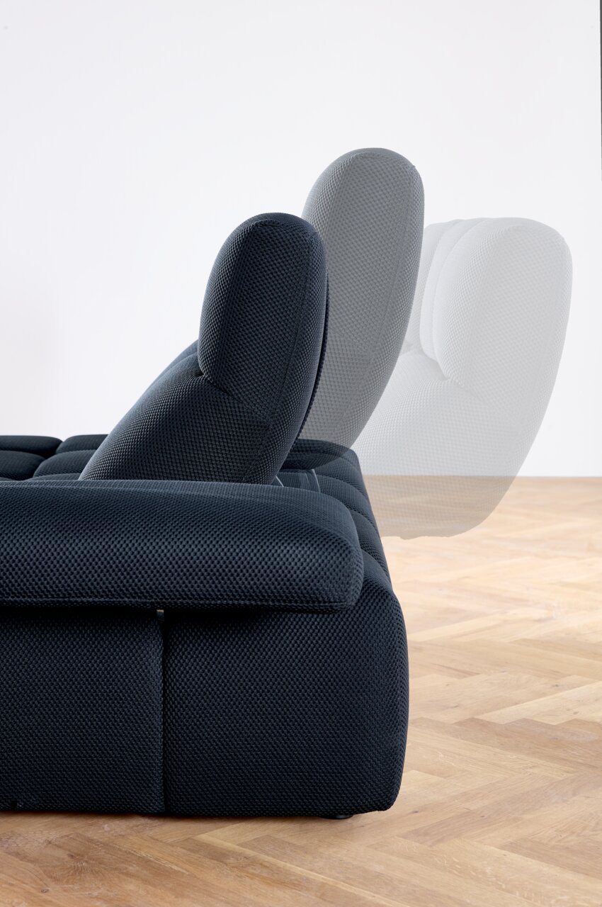 Zijaanzicht van een verstelbare hoekbank met opklapbare rugleuning, bekleed met donkere stof, op een houten vloer.
