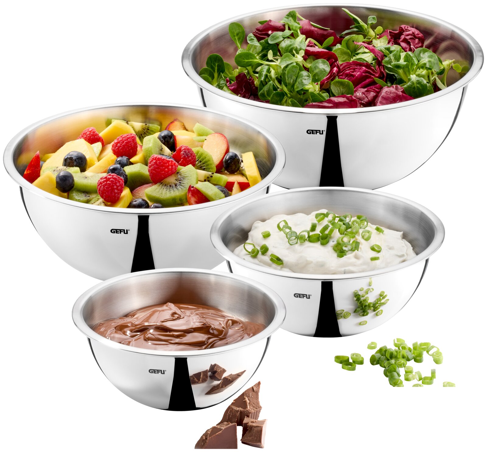 Vier Edelstahlschüsseln in verschiedenen Größen, gefüllt mit Salat, Obst, Schokolade und einer Creme, aus der Vogelperspektive fotografiert.