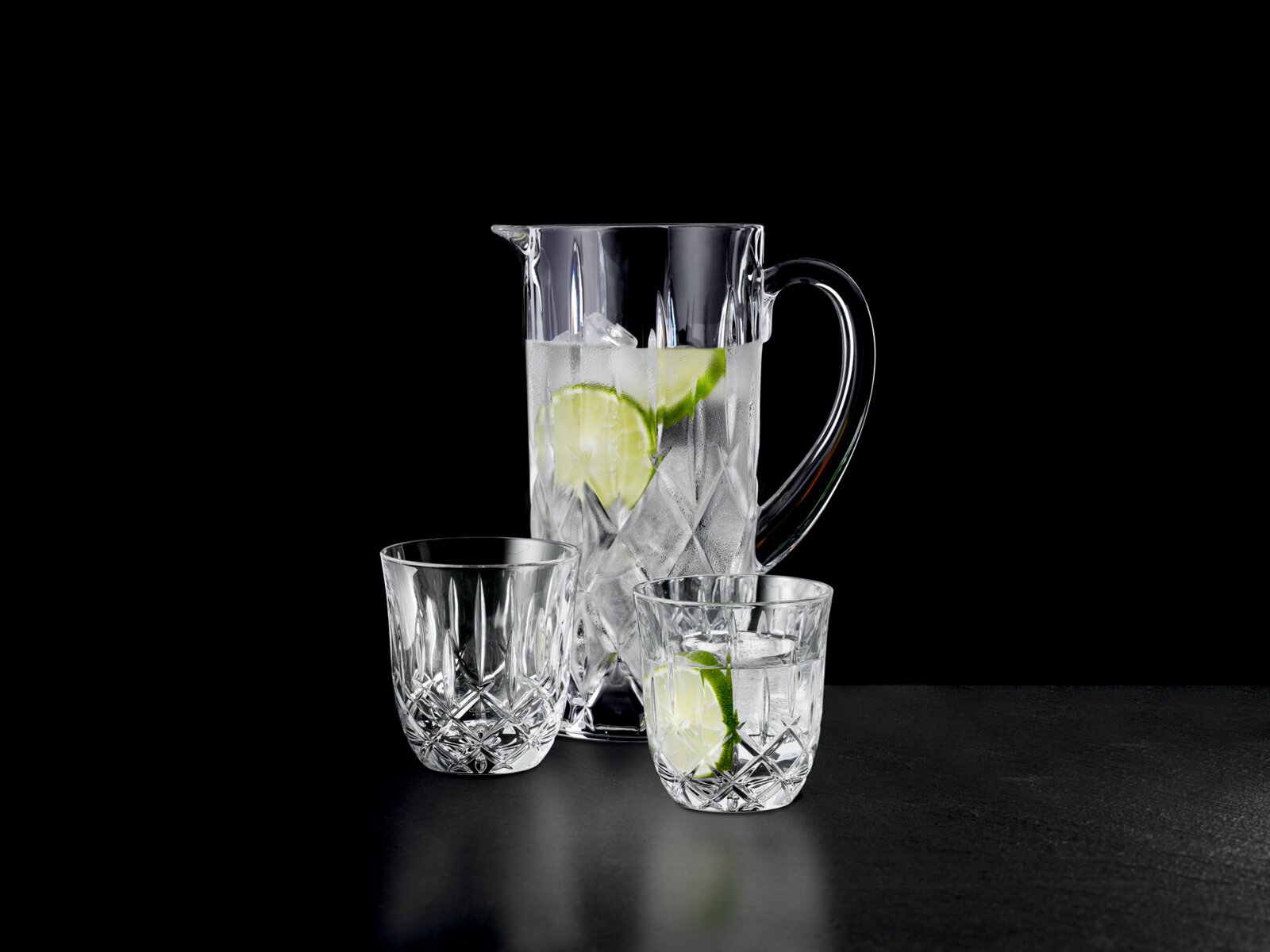 Servies met een kan en twee glazen met ijs en schijfjes limoen, zijaanzicht