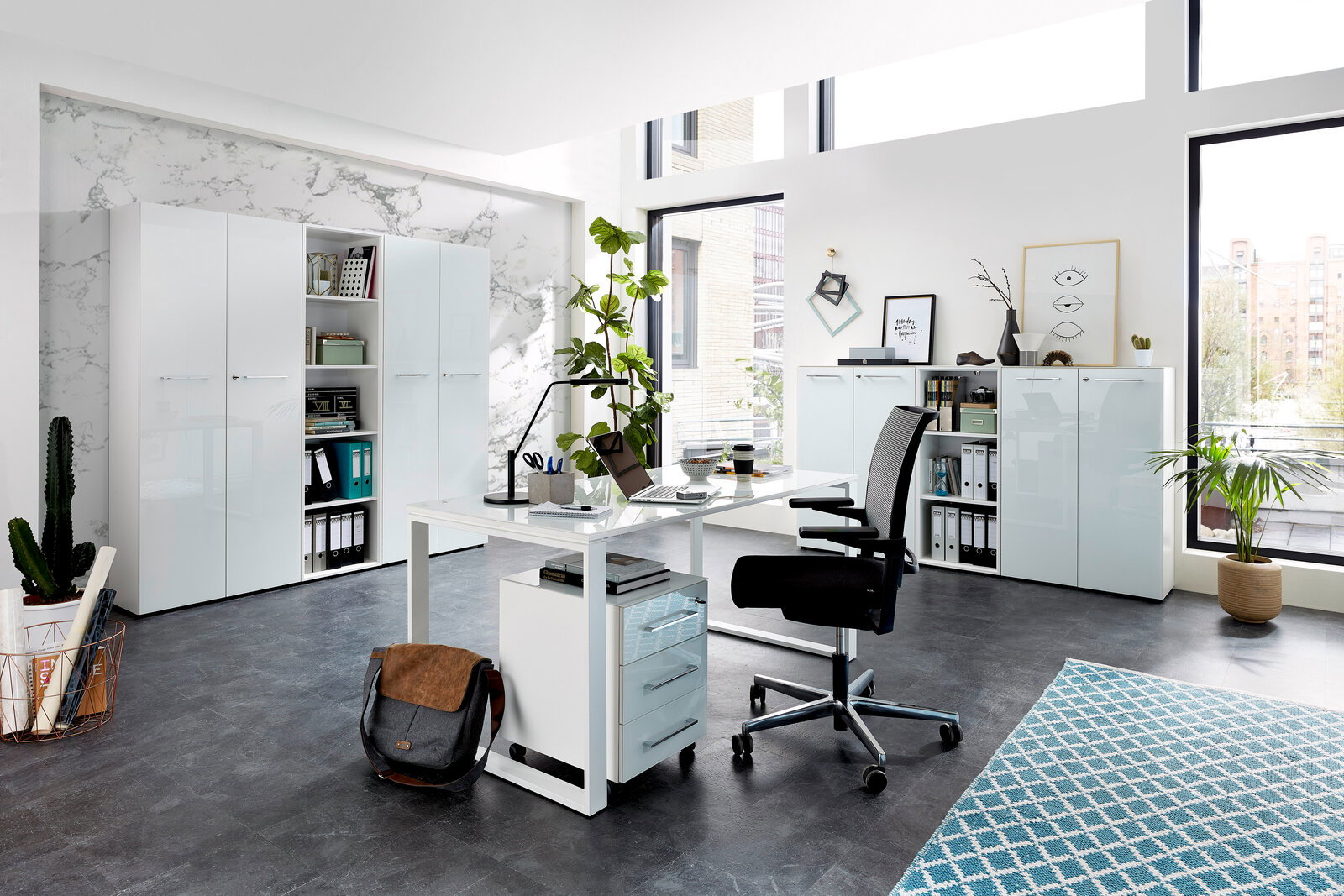 XORA Aktenschrank MATERNO Moderne Büroumgebung mit Schreibtisch, Rollcontainer und Aktenschränken in heller, minimalistischer Gestaltung. Perspektive: seitliche Ansicht des Schreibtischs mit Blick auf die Schränke im Hintergrund.