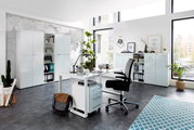 Moderne Büroumgebung mit Schreibtisch, Rollcontainer und Aktenschränken in heller, minimalistischer Gestaltung. Perspektive: seitliche Ansicht des Schreibtischs mit Blick auf die Schränke im Hintergrund.