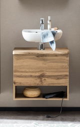 Waschbeckenunterschrank aus Holz mit integriertem Waschbecken, frontal fotografiert. Unter dem Schrank befindet sich ein offenes Fach mit einem Korb und einem Haarglätter.