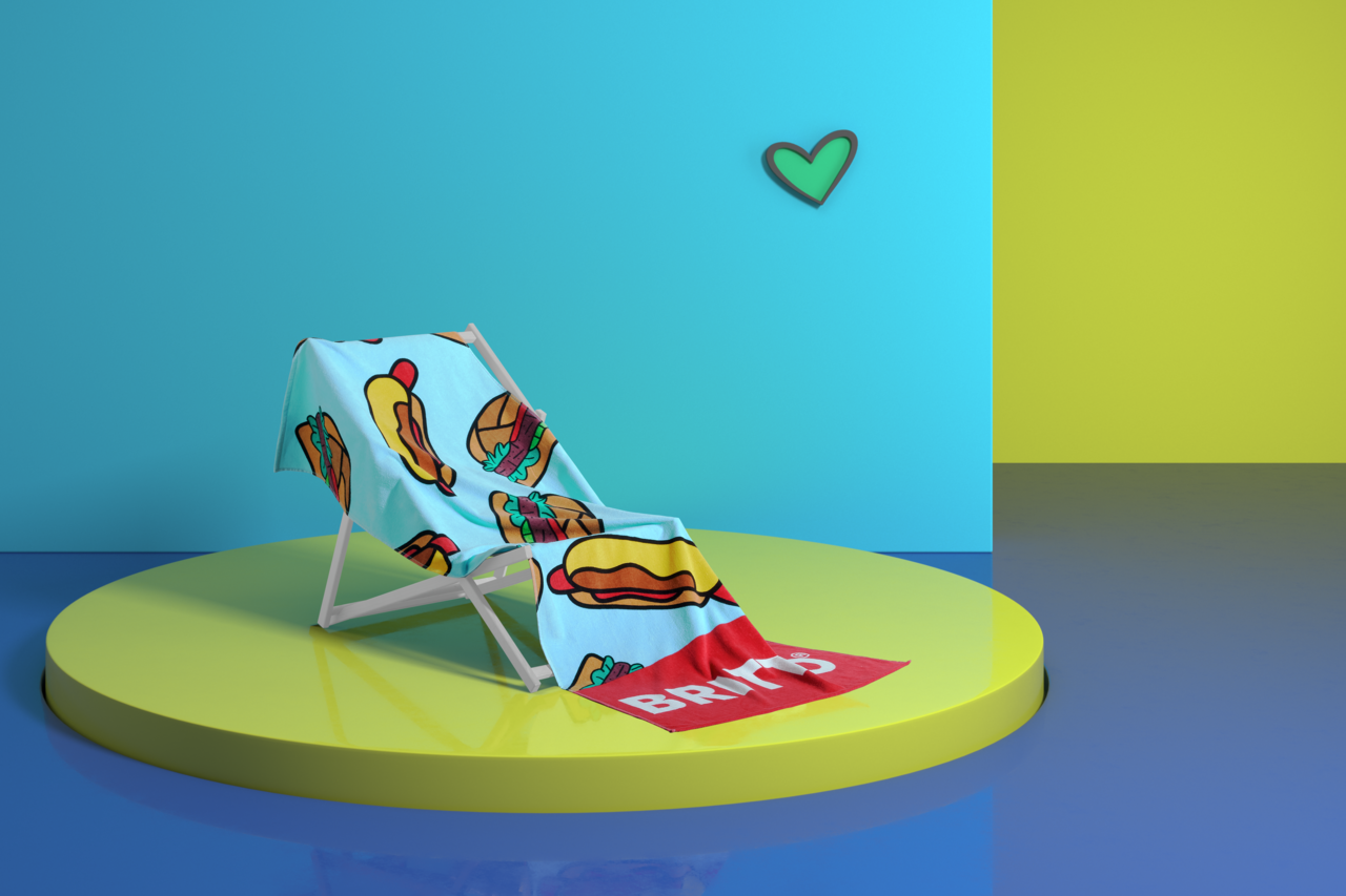 Ein buntes Velourstuch mit Hotdog- und Burger-Motiven liegt auf einem Liegestuhl, präsentiert auf einer runden Plattform vor einem zweifarbigen Hintergrund. Perspektive: seitlich.