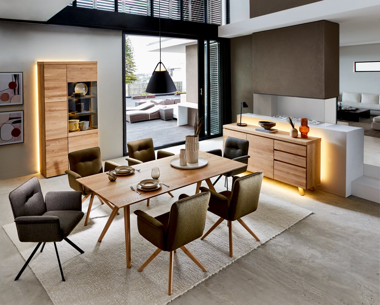 Moderne eetkamermeubels met vitrinekast en dressoir van hout, ledverlichting, eettafel en gestoffeerde stoelen, zijaanzicht.