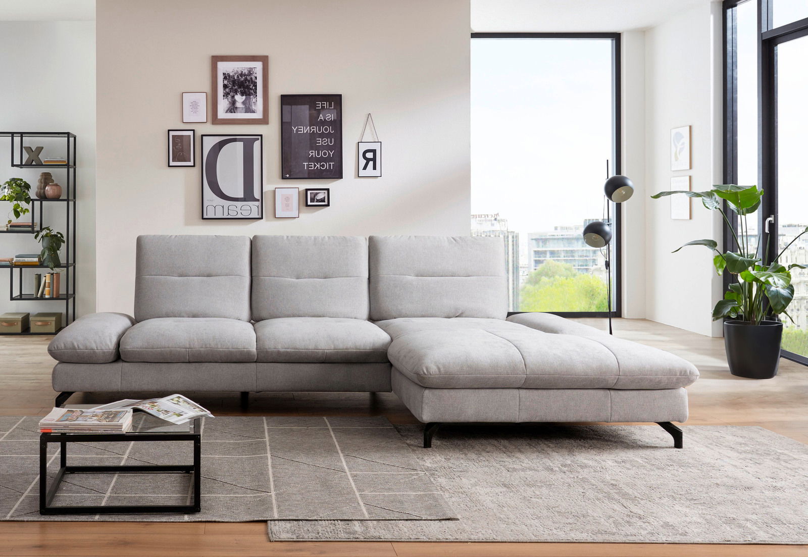 Graues Ecksofa in modernem Wohnzimmer, von vorne betrachtet, mit dekorativen Kissen und einem Couchtisch auf einem Teppich.