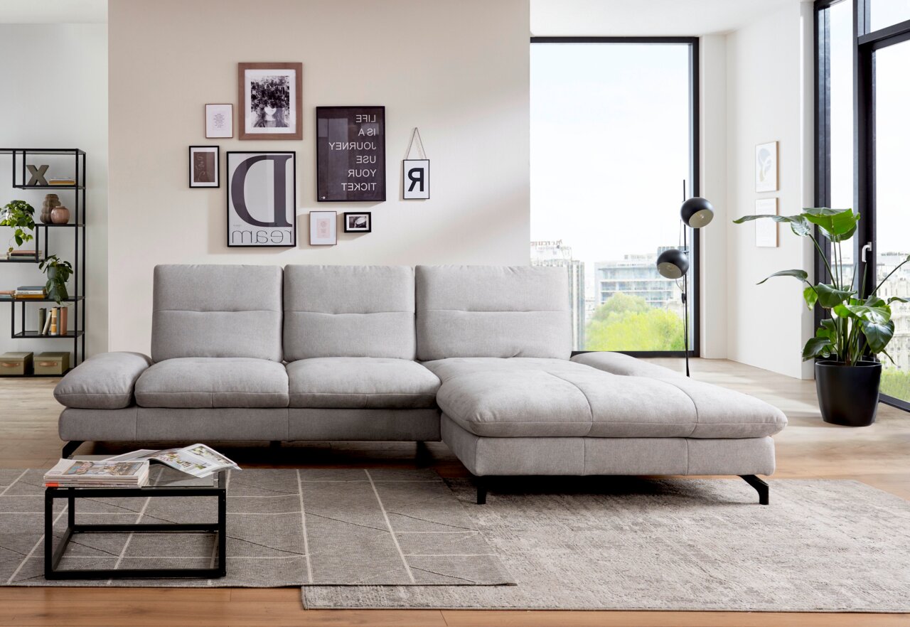 Graues Ecksofa in modernem Wohnzimmer, von vorne betrachtet, mit dekorativen Kissen und einem Couchtisch auf einem Teppich.