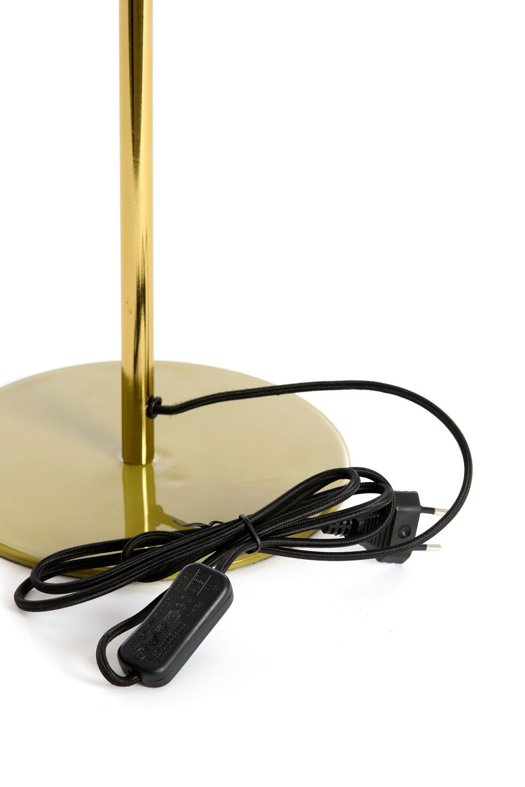 Nahaufnahme der Basis einer goldenen Tischleuchte mit schwarzem Kabel und Schalter, seitliche Perspektive.