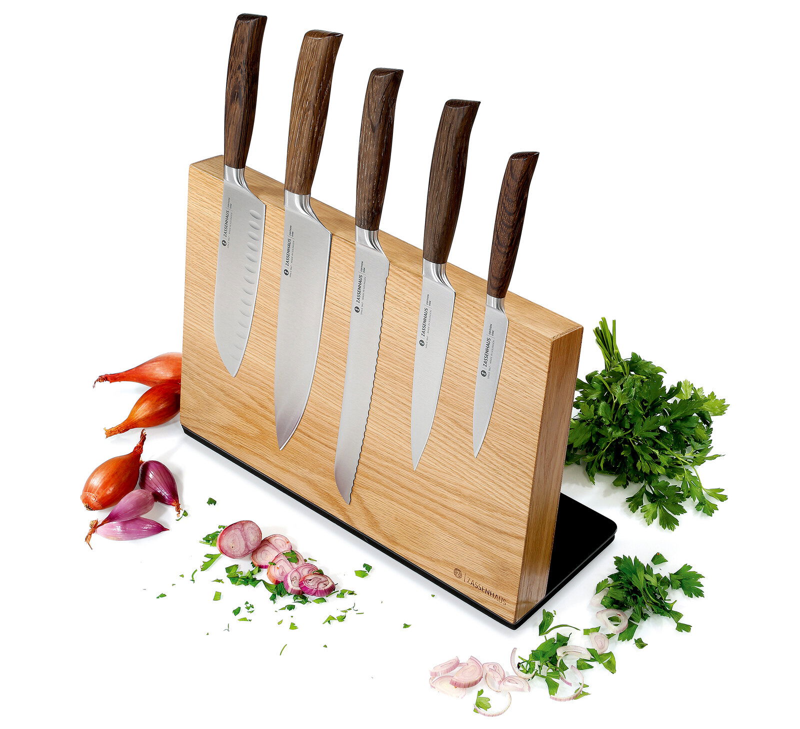 Zassenhaus Magnet-Messerblock STUDIO Magnetischer Messerblock aus Eiche mit fünf Messern, frontal fotografiert, umgeben von frischen Kräutern und Zwiebeln.