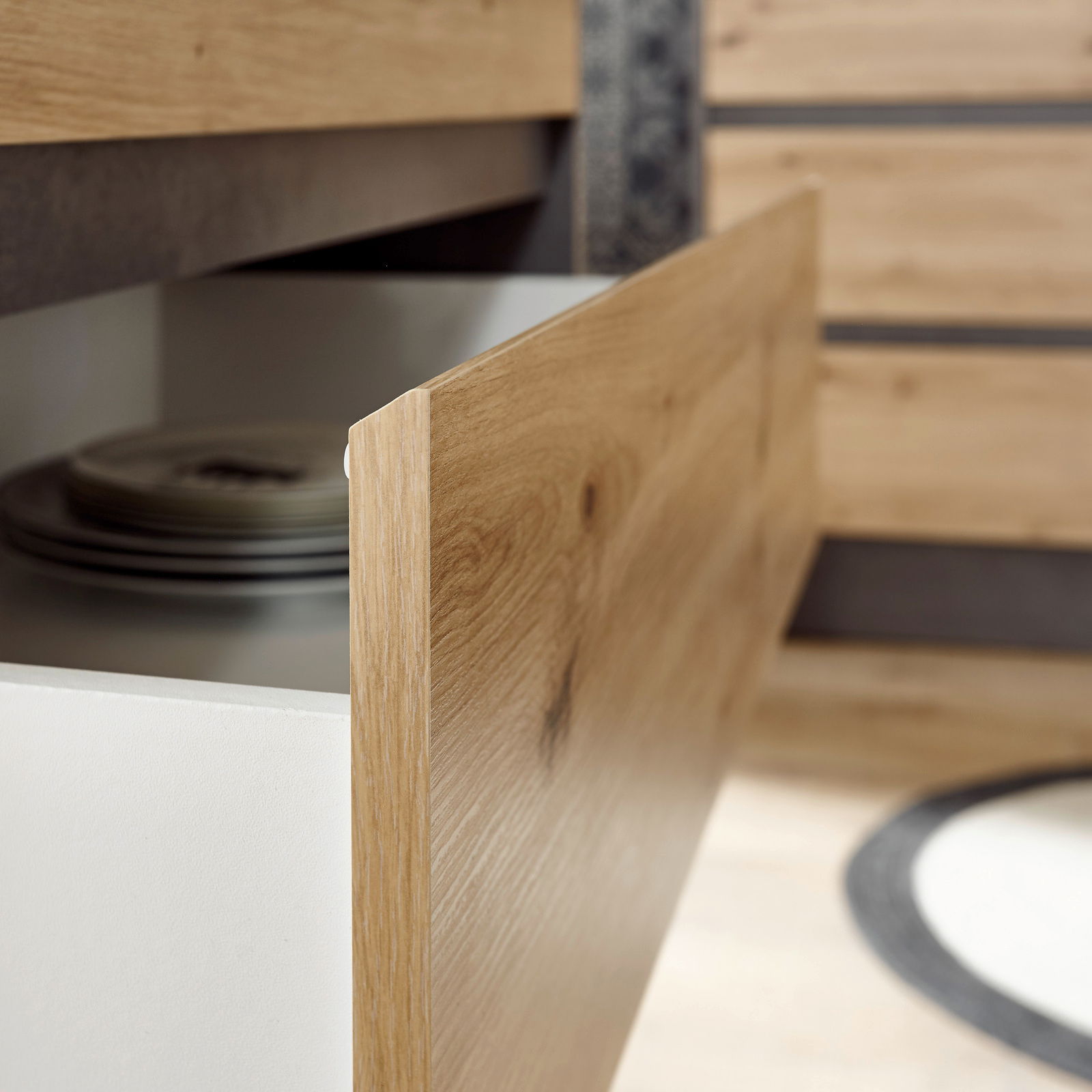 Nahaufnahme einer geöffneten Küchenschublade aus Holz mit sichtbaren Tellern im Inneren, seitliche Perspektive