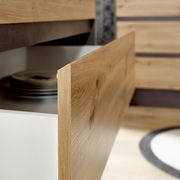 Nahaufnahme einer geöffneten Küchenschublade aus Holz mit sichtbaren Tellern im Inneren, seitliche Perspektive