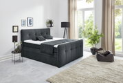 Boxspringbett in einem modernen Schlafzimmer, seitliche Perspektive, mit großen Fenstern und stilvoller Dekoration.