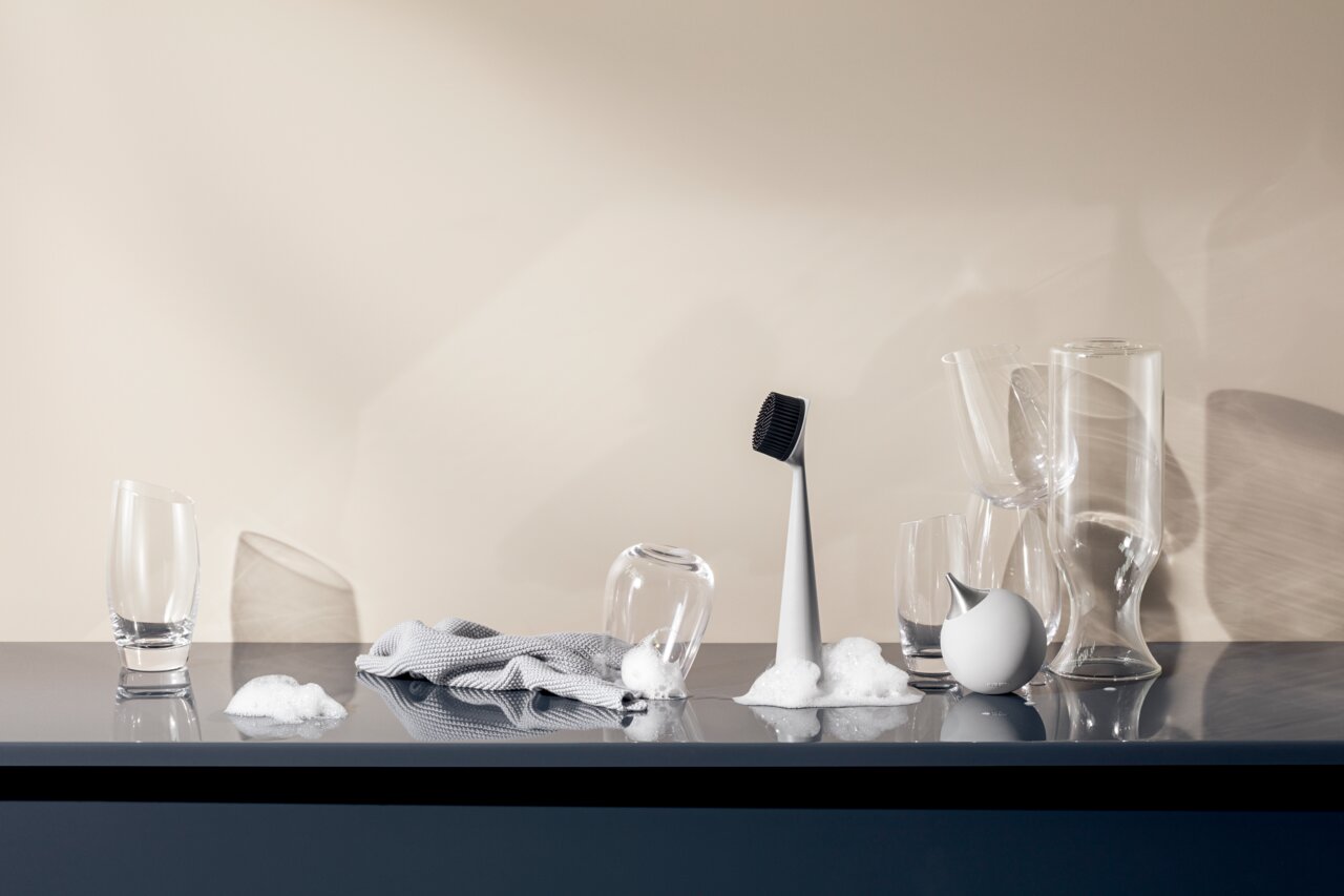 Seifenspender in Marmoroptik, umgeben von Gläsern und Schaum, seitliche Perspektive