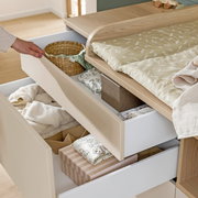 Commode met geopende lades, gevuld met babyspullen, gezien vanuit bovenaf.