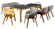 Esszimmer mit einem Tisch aus Holz und sechs Armlehnstühlen in verschiedenen Farben, seitliche Perspektive